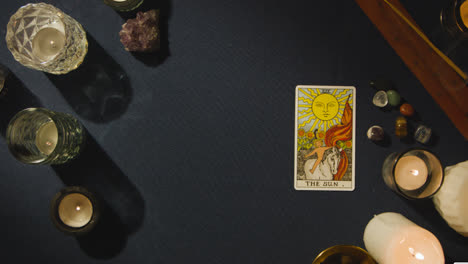 Overhead-Shot-Of-Person-Giving-Tarot-Card-Reading-Laying-Down-The-Sun-Card-On-Table-1